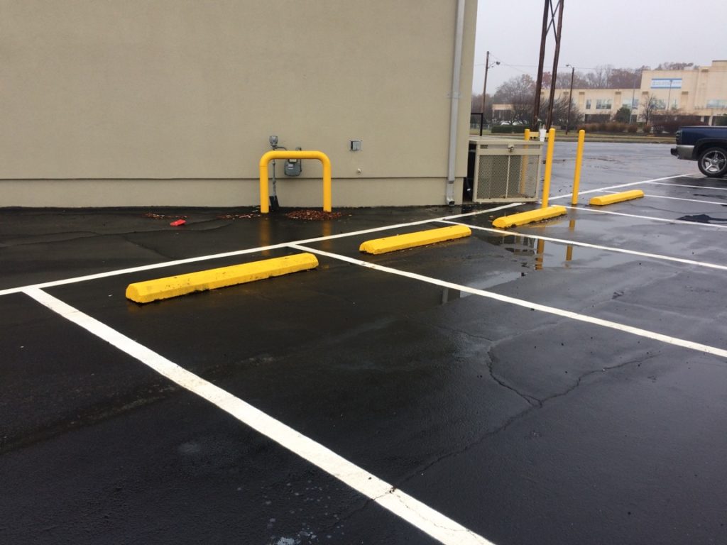 Commercial parking lot with fresh striping and protective bollards by American Asphalt