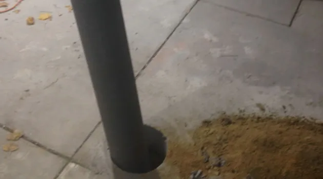 Protective bollard set plumb in the asphalt surface