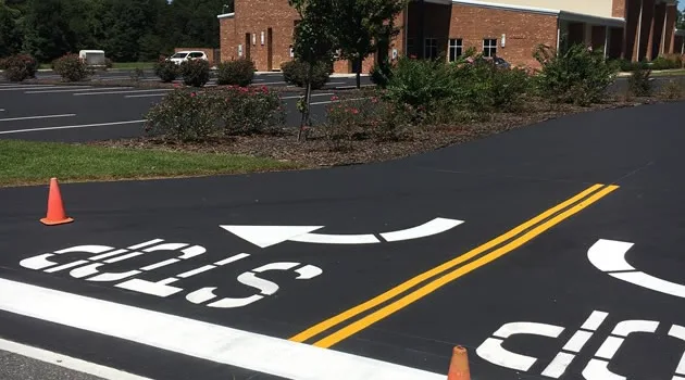 Repainted STOP stencil on freshly sealed asphalt