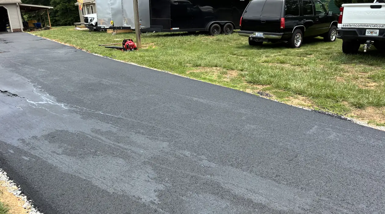Fresh black asphalt driveway with clean stone shoulders