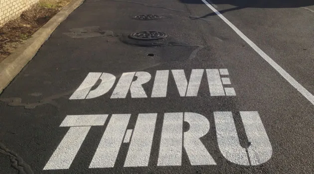 Custom DRIVE THRU stencil freshly painted on sealed asphalt