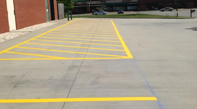 Crisp yellow hatch striping on a newly sealcoated lot